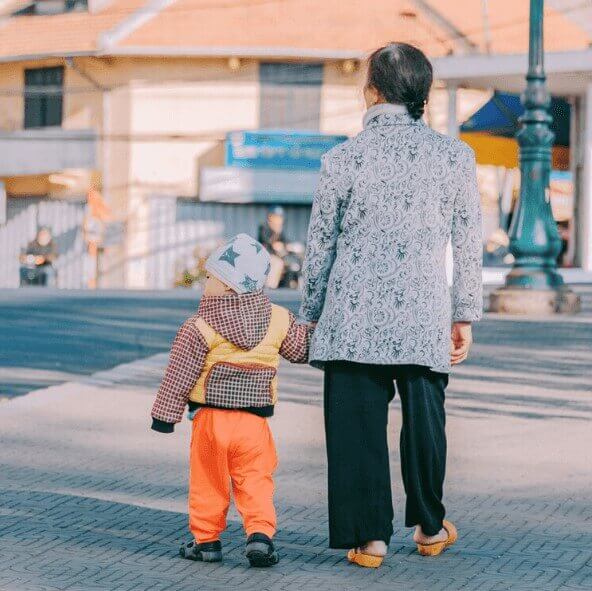 A grandma is outside holding hands with her grandson