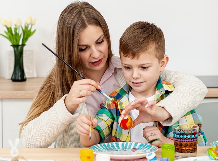 Mother showing son how to paint an egg