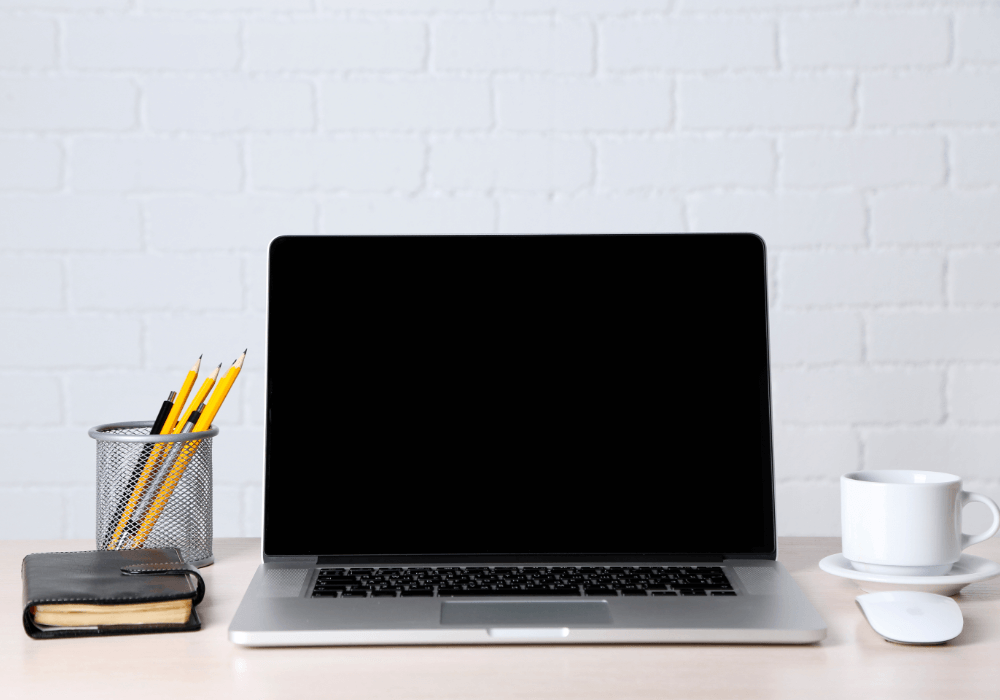 Laptop, pencil holder, and tea cup on a desk