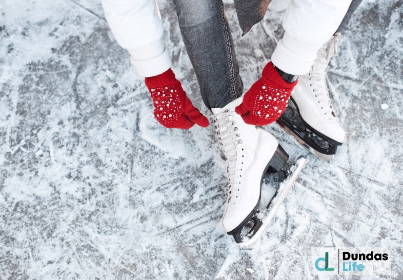 Girl tying shoelaces on ice skates before skating on the ice rink